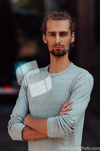 Image of Portrait of a young successful businessman with crossed arms in front of the company