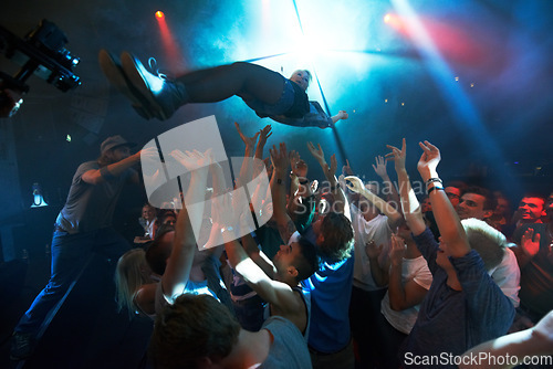 Image of Music artist, stage dive and concert for party, nightclub or dance festival in the crowd or audience indoors. DJ, music concert and crowds of people ready to catch performer in celebration for event