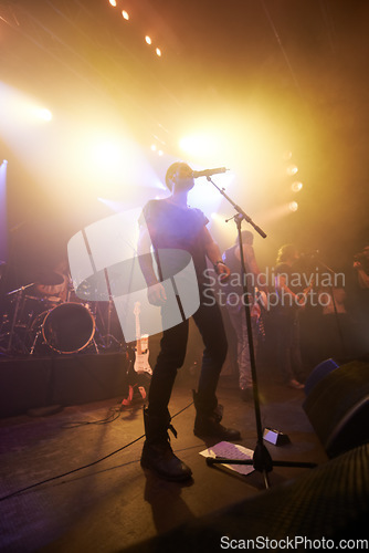 Image of Music, rock and stage with man and microphone singing for concert, festival and party event. Light, celebration and performance with singer and band at nightclub for disco, techno or new year show