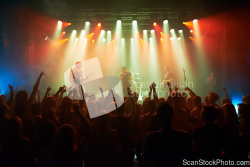 Image of Rock, band and crowd of people at concert for stage performance, party dance and new year or holiday festival in dark. Dancing, singing and celebrity or musician with night club music for an audience