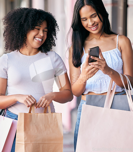 Image of Woman, friends and phone with shopping bags, smile and enjoying free time or social media together in the city. Happy women smiling in happiness for online sale, deal or discount on mobile smartphone