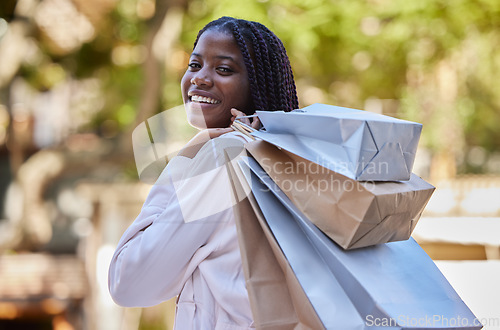 Image of Black woman, shopping and bags with smile for luxury, self love or self care in the outdoors. Portrait of African American female shopper smiling carrying gifts and enjoying shop or buying spree