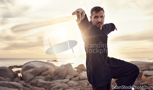 Image of Man, sword and zen thai chi balance on beach for fitness training, chakra healing or spiritual energy. Thai wellness workout, meditation exercise and therapy with weapon for self defence at ocean