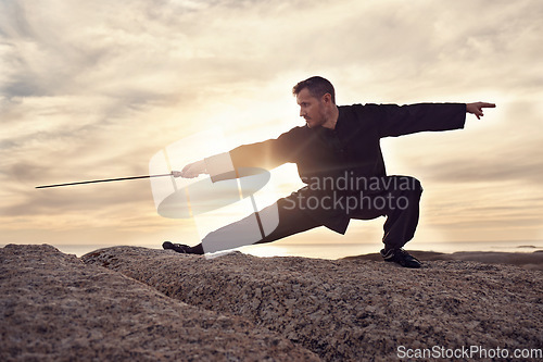 Image of Martial arts, sword and tai chi, meditation and training at beach, sunset and outdoor in summer in Australia. Man, mindfulness and calm with balance alone in nature, ocean and meditate fo wellness