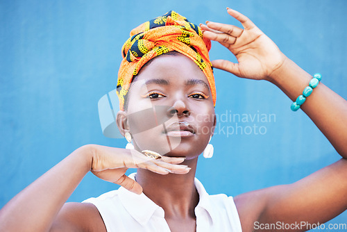 Image of Fashion, Africa and portrait of black woman on blue background with natural beauty, glowing skin and makeup. Hands frame face of girl with African style or design cosmetics, head scarf and jewellery