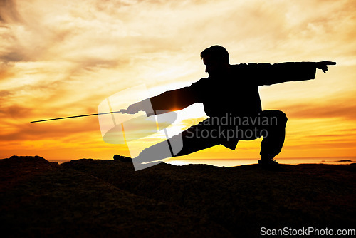 Image of Sunset, sport and man doing tai chi with a sword on a hill for exercise and fitness workout. Silhouette, training and sports exercising male at sunrise for chi gong practice for health and wellness