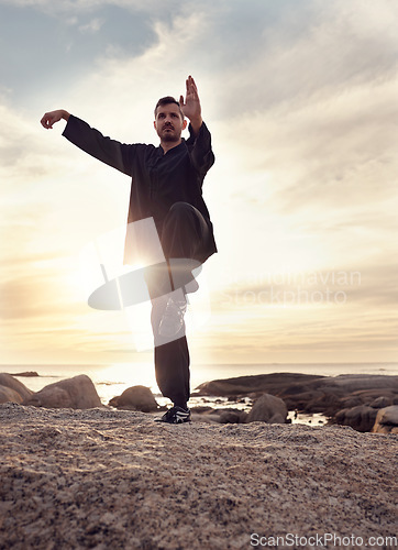 Image of Man, tai chi and meditation while calm, mindfulness and wellness for mindfulness, balance and relax at the beach. Male meditate, training and spiritual faith outdoor at ocean during sunset in summer