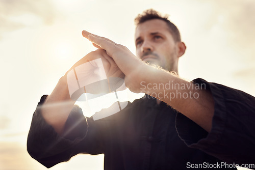 Image of Karate, martial arts and hands of man at sunrise for taekwondo training, exercise and workout in nature. Sports, fitness and male athlete with sensei pose for balance, mindfulness and motivation