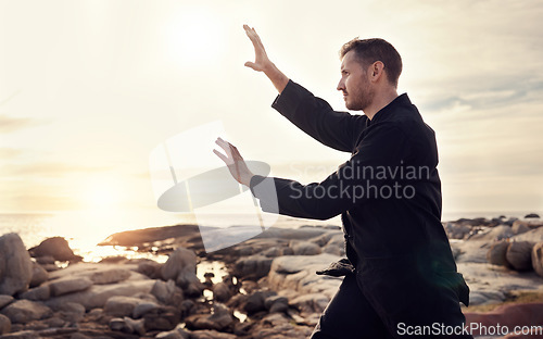 Image of Nature, zen and tai chi, man on beach for balance and peace for mental wellness or control of body and mind. Spiritual health, fitness and meditation, energy and self care on rocks at sea in sunset.