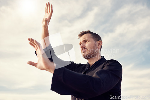 Image of Karate man, fitness and exercise against a cloudy sky with lens flare for spiritual workout, martial arts and training outdoor. Athlete male ready to fight tai chi, chi gong or taekwondo with hands