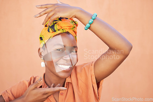 Image of Face portrait, fashion and black woman with turban in studio on an orange background. Beauty pose, hands frame and makeup of happy female model from Nigeria in stylish traditional African head scarf.