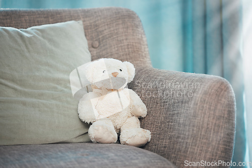 Image of Lonely, loss and adoption with a teddy bear abandoned on a sofa in an empty living room of a home. Lost, alone and grief with a stuffed animal sitting on a couch in the lounge of a house alone