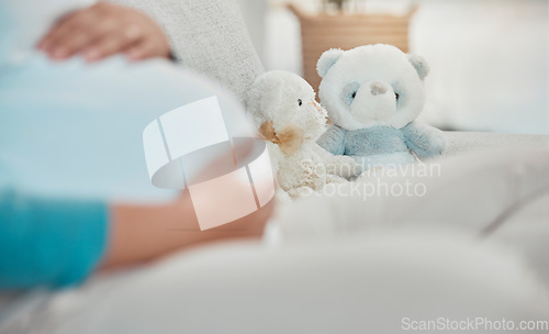 Image of Mother, stomach and teddy bear in the background while relaxing on the sofa at home. Pregnancy, maternity and female rest in her house with toys while preparing for parenthood and motherhood