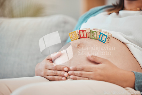 Image of Pregnant woman, stomach and baby blocks in home for girl announcement on sofa in living room. New mother, parenthood love and childcare or pregnancy support, relax and calm mom with hands on belly