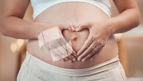 Image of Woman, hands or heart shape on pregnant stomach in house, home living room or prenatal care clinic. Zoom, pregnancy or mother touching belly in love, care or trust of baby health, support or security