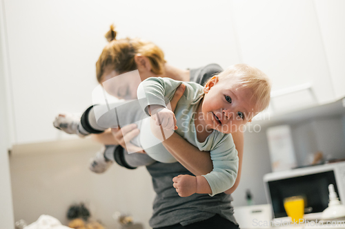 Image of That awkward moment when your mom sniffs your butt. Mother holding her baby, sniffing stinky diaper of her little boy checking if it is time to change it.