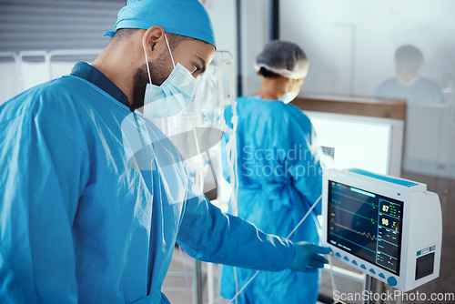 Image of Doctor, hospital and medical machine with monitor screen during surgery for dialysis, healthcare and analysis in a room with a face mask and scrubs. Surgeon man pressing button on cardiology device