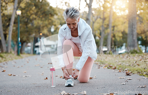 Image of Fitness, park and senior woman getting ready for running, exercise or outdoor workout with water bottle for fashion, gear and wellness. Nature road with elderly runner or old woman shoes or sneakers