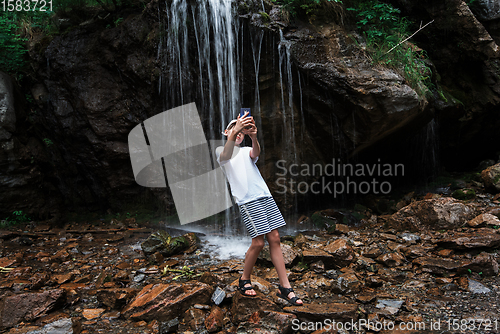 Image of Boy tourist taking selfie photos with a smartphone at the waterfalls