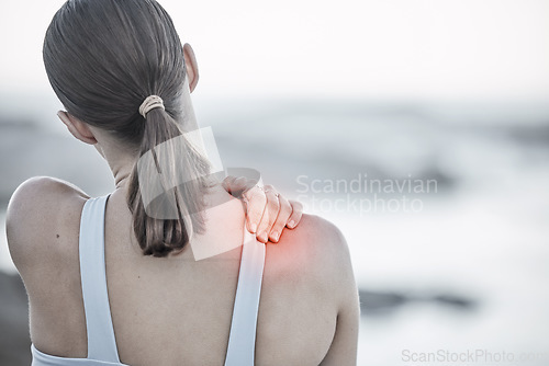 Image of Back, pain and injury with a sports woman holding her shoulder during an exercise workout on the beach. Fitness, health and wellness with a digital CGI or overlay on a female hand outdoor in nature