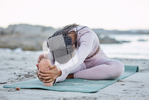 Image of Yoga, fitness and beach with a black woman stretching on an exercise mat for health or wellness in nature. Workout, training and balance with a female yogi doing a warm up by the sea or ocean