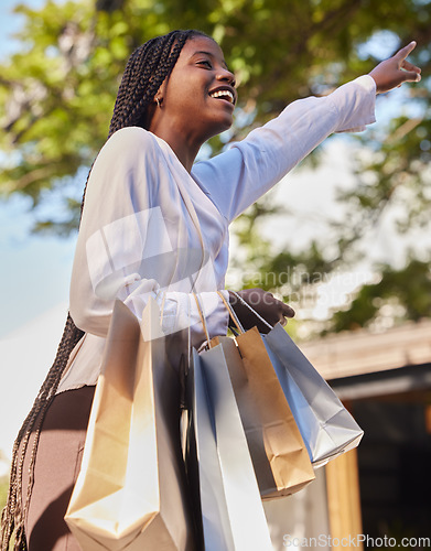 Image of Black woman, shopping bags and outdoor on city street while happy and hailing for a taxi or cab to travel on consumer journey. African female with hand up for transport with a smile after retail sale