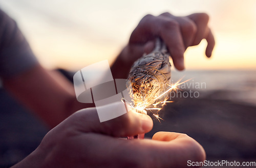 Image of Hand, flame and sage burning at the beach for a spiritual ritual and meditation practice. Herb, finger and lighter with a plant being burned for zen meditative, mental health and chakra ceremony