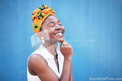 Image of Fashion, style and trendy african woman on a blue wall or background with a headwrap. African american headwear, trend and beauty with a female fashion stylist in contemporary apparel and jewelry