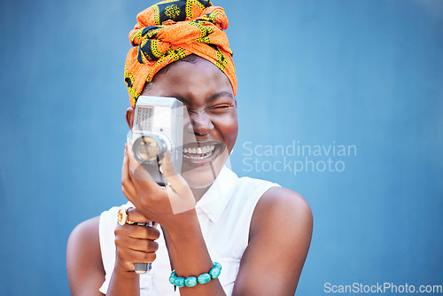 Image of Face, photographer and black woman with camera in studio isolated on a blue mock up background. Photography, tech and happy female from Nigeria with camcorder taking pictures, photo or photographs.