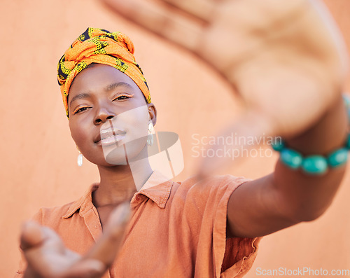 Image of Black woman, face portrait and hands frame for fashion aesthetic, african culture and turban in studio with orange background. Nigeria, cosmetics makeup and traditional head scarf or playful gesture