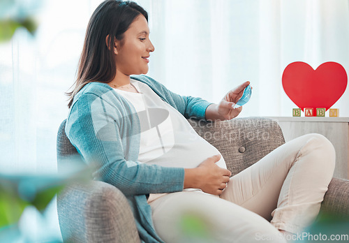 Image of Pregnant woman, ultrasound and mother on sofa in home looking at picture. Pregnancy, sonography and happy female in house with photograph, sonogram and love, care and affection for baby in stomach.