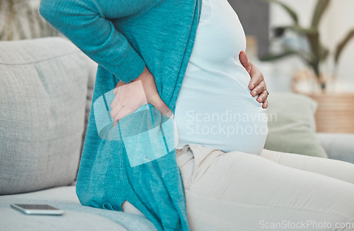 Image of Back pain, pregnancy and woman relaxing on a sofa in her living room at her modern house. Medical emergency, injury and pregnant lady with a swollen body, physical inflammation and backache at home.