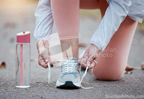 Image of Senior woman fitness, exercise and shoes with hands tying laces while running on a concrete road or street. Workout, training and cardio with a elderly female hand getting ready for a run routine