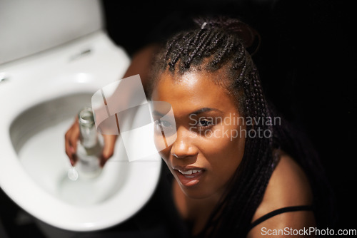 Image of Drunk, party and bathroom nausea of a black woman with a alcoholic problem and addiction. Toilet, drinking abuse and African female portrait with a beer bottle at night with alcohol drink feeling ill