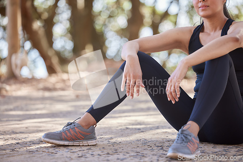 Image of Nature, hiking and woman stop for breath or sitting on ground in forest to relax on outdoor run or workout. Health, fitness and wellness, a tired girl on hike on break from running exercise on path.