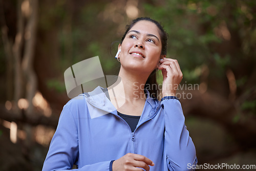 Image of Forest, fitness and woman listening to music for nature calm, peace and zen podcast with inspiration for sports training, hiking or running. Happy woman or athlete with audio technology in the woods