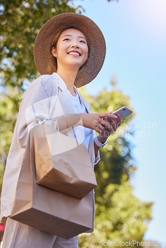 Image of Phone, asian woman and shopping bag with happy, smile and technology with 5g web outdoor. Happy young person texting, internet networking and doing a social media app scroll online with happiness