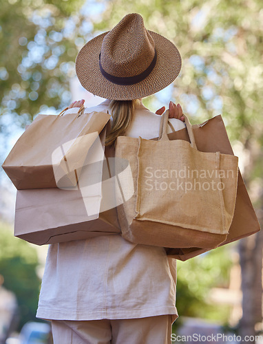 Image of Sun, trees and woman with bags from shopping from back walking in park on holiday. Summer, nature and travel, girl with shopping bag from luxury designer boutique buying gifts on vacation garden path