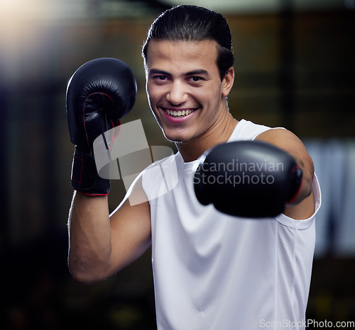 Image of Portrait, fitness and boxing man punching with boxing gloves in a sport gym for health. Athlete, boxer and face of strong male personal trainer prepare for a fight or kickboxing and muay thai event