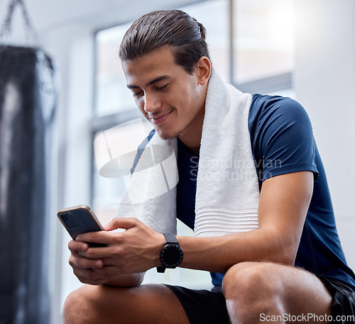 Image of Fitness, phone and man relax in gym tracking workout, exercise or progress on app. Tech, sports and happy male with towel and mobile smartphone for internet browsing, text messaging or social media.