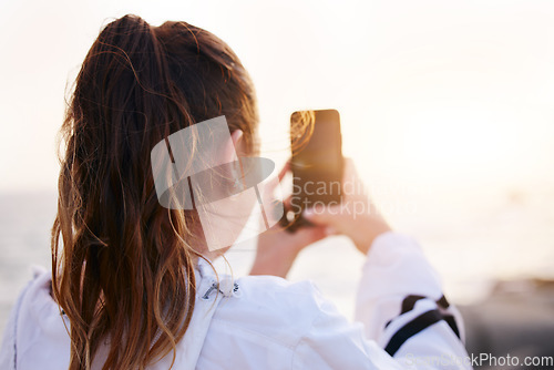 Image of Woman, back or phone picture of beach sunset by ocean or sea in nature environment, holiday vacation or Canada travel location. Student, tourist or influencer on mobile photography technology or vlog