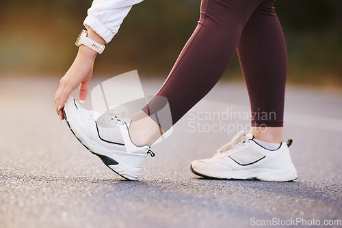 Image of Feet, fitness and stretching woman in street for running, outdoor training and exercise with sneakers, shoes or sports gear marketing. Hand, foot and sports, athlete or runner on road for workout