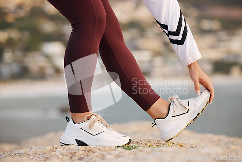 Image of Stretching, legs and woman on a beach rock, start fitness and yoga exercise in nature of Portugal. Warm up, training and feet of an athlete at the ocean for spiritual health, cardio or pilates