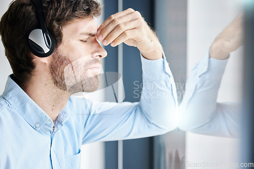 Image of Headache, stress and call center man in office feeling exhausted, tired or fatigue. Crm, customer service and male telemarketing consultant with depression, anxiety and burnout in company workplace.