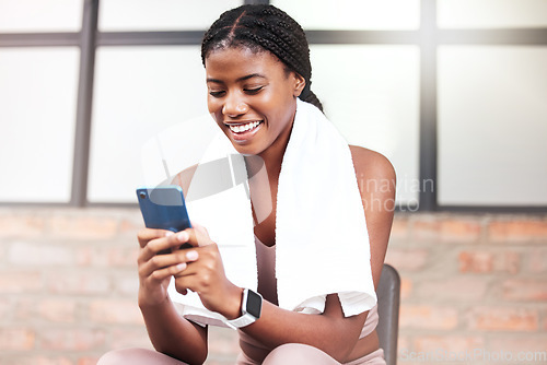 Image of Fitness, phone and black woman relax in gym tracking workout, progress or exercise on app. Sports, mobile tech and happy female with towel and smartphone internet browsing, social media or texting.