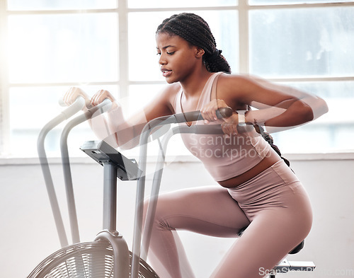 Image of Motion blur, exercise bike and black woman in gym for workout, cardio training and moving with speed, energy and motivation. Fitness girl, stationary cycling machine and air bike, wellness and action