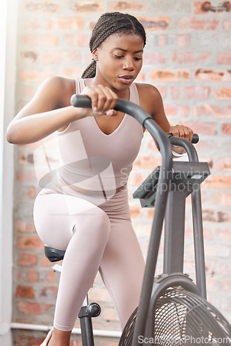 Image of Gym, fitness or black woman on a bike machine in training, cardiovascular exercise or full body workout. Bicycle, energy or African girl athlete cycling for a healthy heart, sports or speed challenge