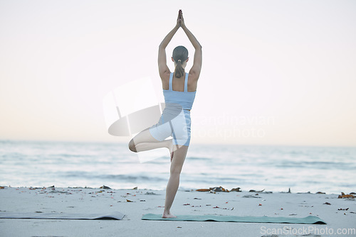 Image of Yoga, fitness and woman doing beach workout for balance, freedom and mindfulness in morning with tree pose for health and wellness. Back of female doing pilates, chakra and zen training at sea