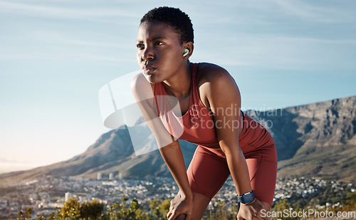 Image of Tired, music and mountain with black woman running in nature for sport, endurance and breathing. Podcast, streaming and mobile radio with runner listening to earphones while training, cardio and goal