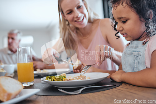 Image of Family, mother and cutting food for girl while having lunch at dinner table in home. Love, foster care and happy mom helping child with eating, smiling and enjoying a delicious meal together in house